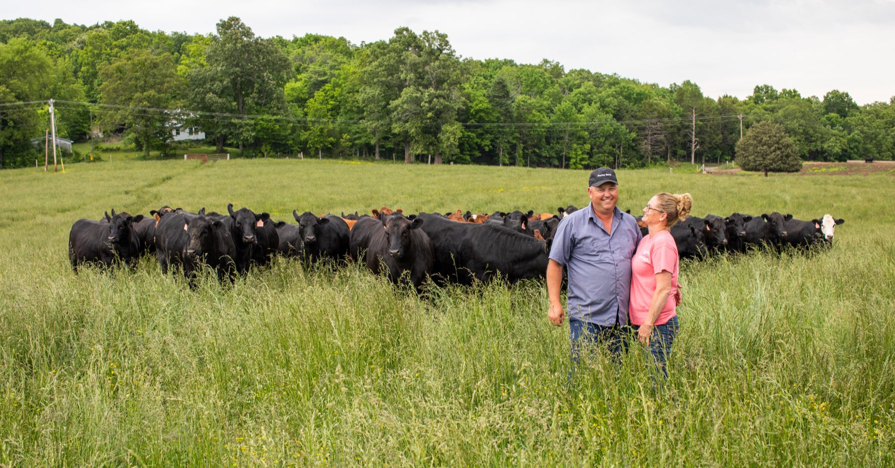 Joey and Kim Rittenberry standing in their pasture in front of their cattle