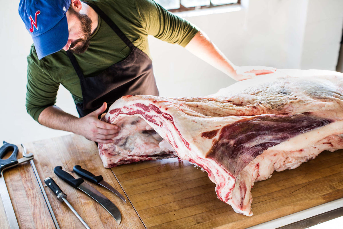 Butcher examining a large beef primal on the butcher block